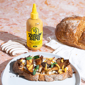 Savory toast topped with a mushroom medley, cottage cheese, a drizzle of Yellowbird Garlic Shiitake Hot Sauce, and fresh sprouts on toasted sourdough.