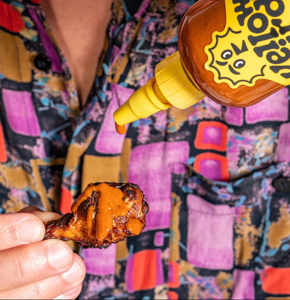 Yellowbird Small Batch Serrano Coconut Hot Sauce drizzled onto a crispy air-fried chicken wing